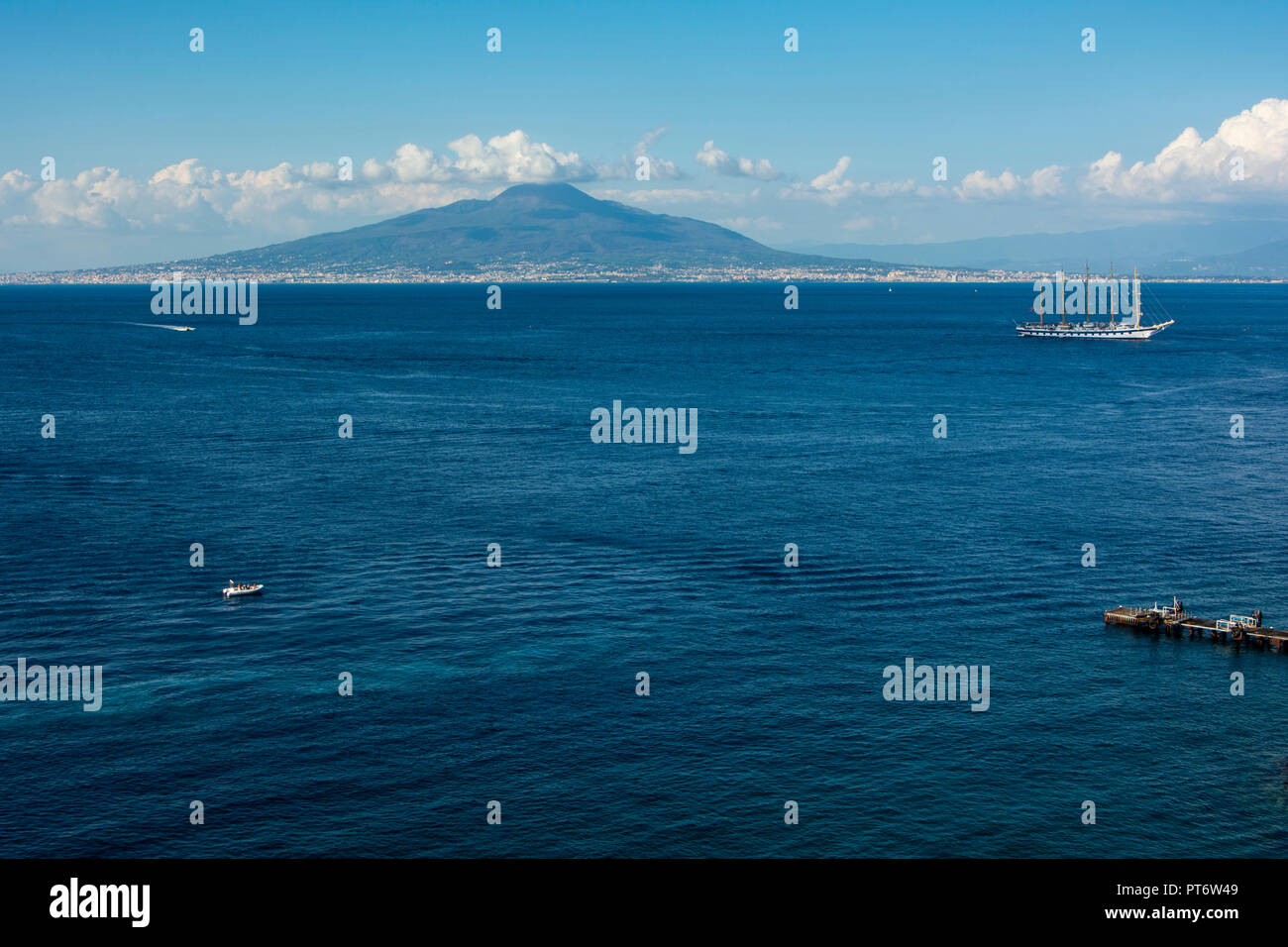 Vesuv in der Nähe von Sorrent auf einem hellen, sonnigen Tag mit Wolken und einem großen Segelschiff im Vordergrund. Stockfoto