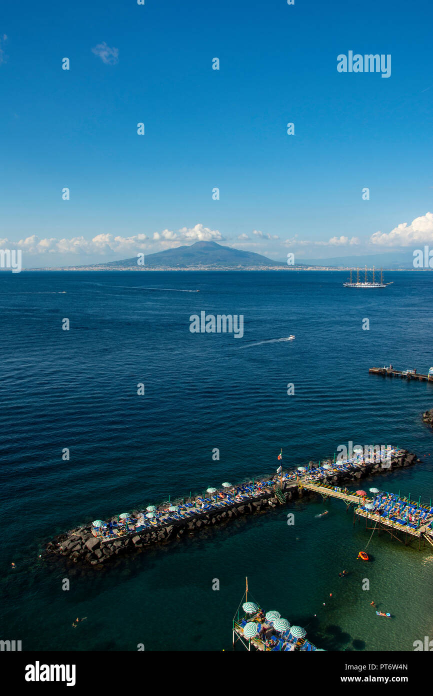 Vesuv in der Nähe von Sorrent auf einem hellen, sonnigen Tag mit Wolken und einem großen Segelschiff im Vordergrund. Stockfoto