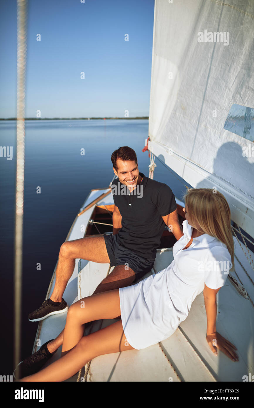 Lächelnde junge Paar sitzen zusammen auf dem Deck der Yacht und genießen Sie einen Nachmittag Segeln Stockfoto