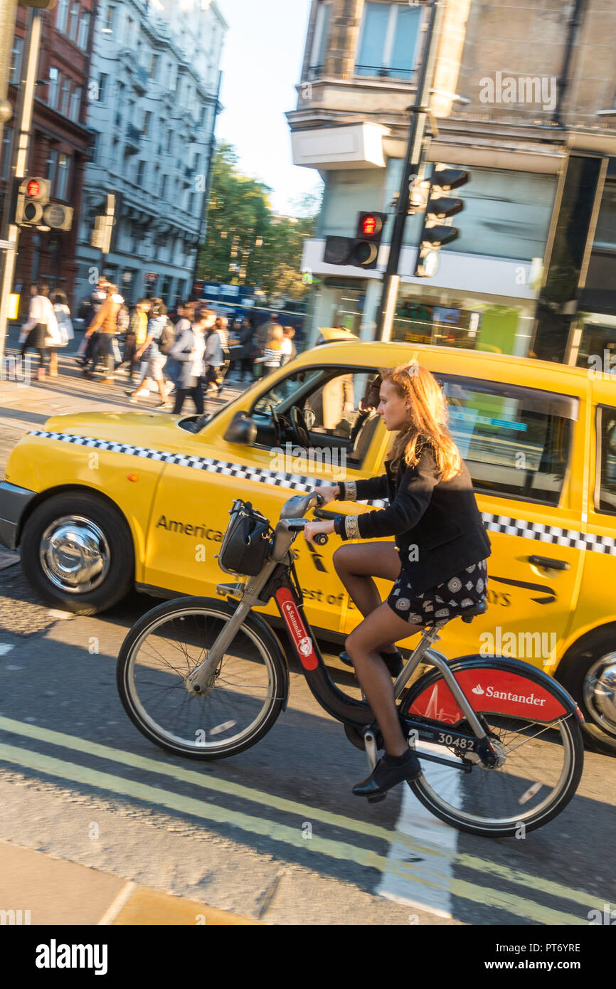 Gelbe Taxi vorbei an eine Frau auf einem Fahrrad Santander in London, UK, Europa. Stockfoto