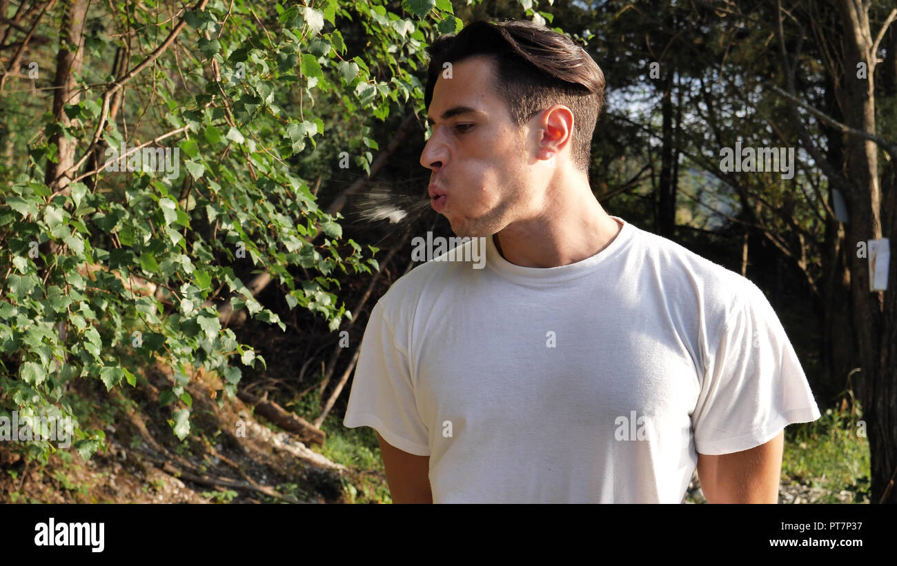 Junger Mann Husten in der Natur im weißen T-Shirt Stockfoto