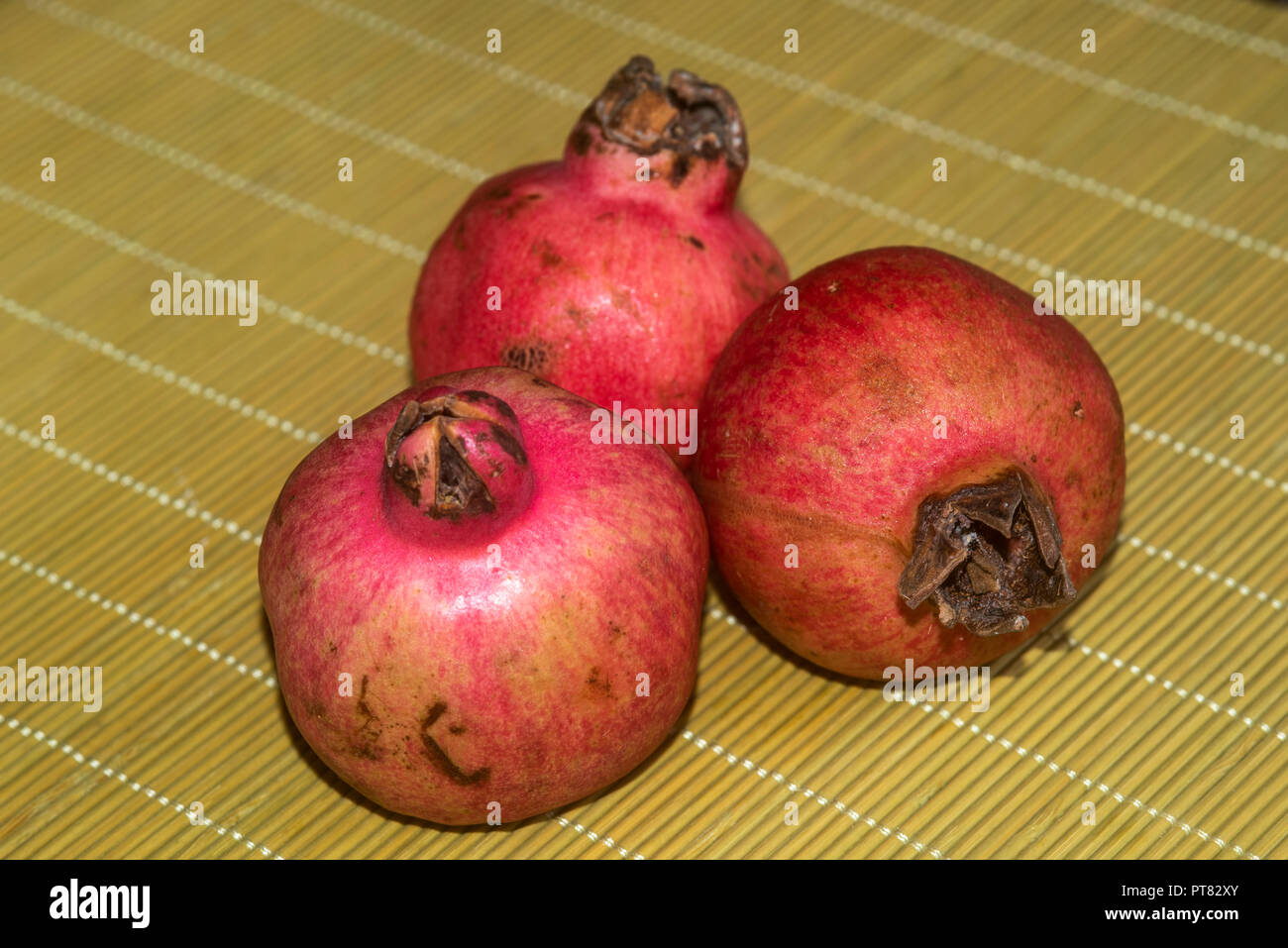 Drei Granatäpfel an einem Bambus Tisch mat Stockfoto
