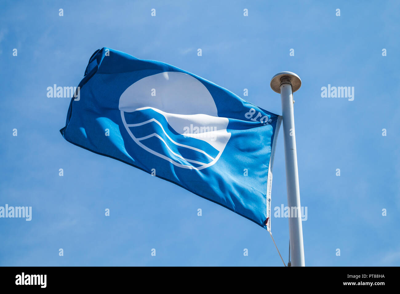 Strand mit Blauer Flagge, wehende Flagge über bewölkter Himmel Stockfoto