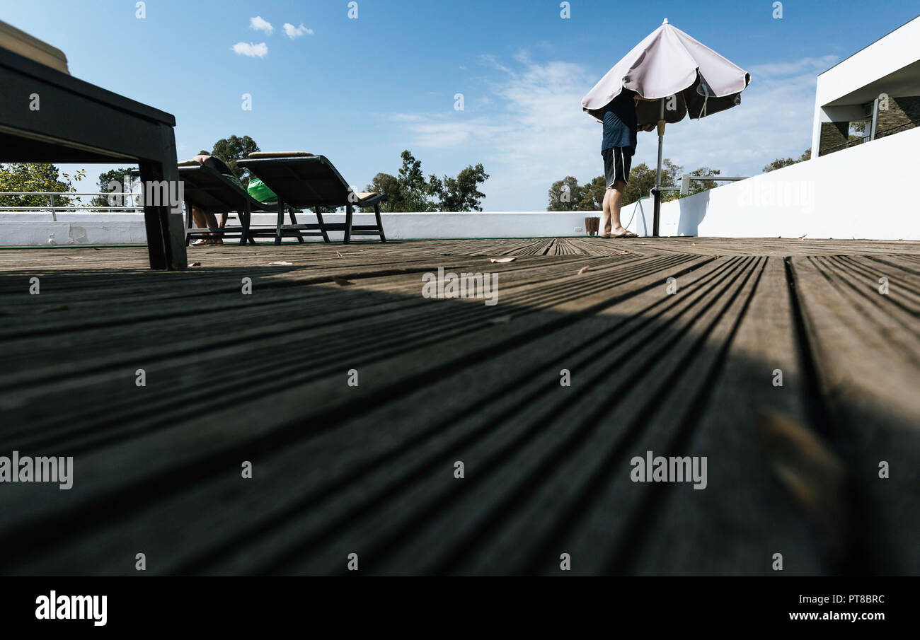 Mann, der mit seinem Kopf in den Regenschirm und Frau zurück in die Hängematte mit blauem Himmel Hintergrund sitzen Stockfoto