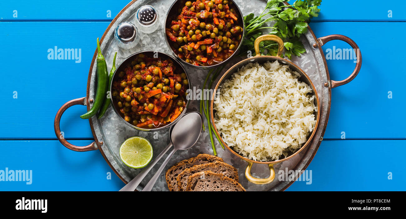 Banner von vegan Curry mit grünen Erbsen und Basmatireis auf einem blauen Tisch Tablett serviert, gesunde indische Speisen Stockfoto