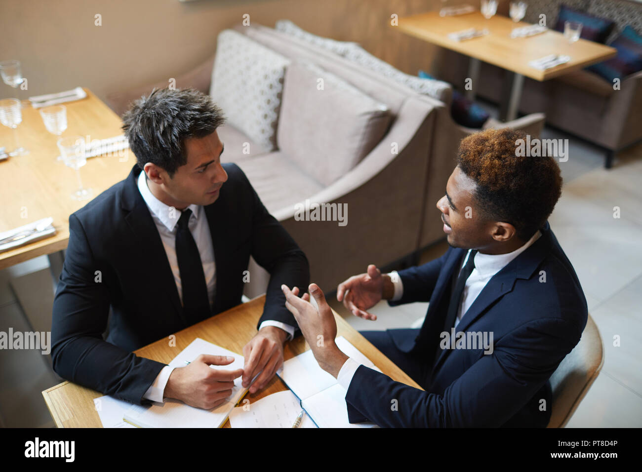 Ernsthafte zuversichtlich, multi-ethnischen Geschäftsleute im Anzug an einem Tisch sitzen und diskutieren Strategien im Cafe: afrikanischer Mann Gestik, die Hände bei der Erklärung der p Stockfoto