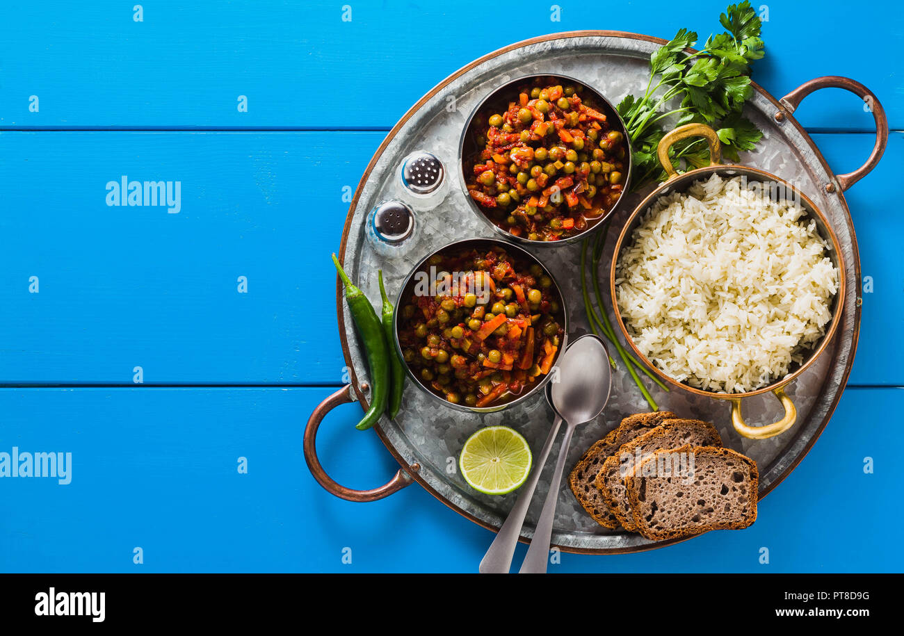 Vegan curry mit grünen Erbsen und Basmatireis auf einem blauen Tisch Tablett serviert, gesunde indische Speisen, kopieren Raum Stockfoto