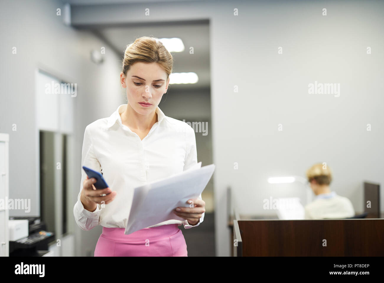 Junge elegante Geschäftsfrau mit Papieren wählen die Telefonnummer eines Kollegen für eine Rückfrage anrufen Stockfoto