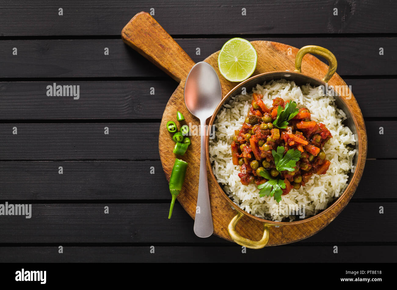 Vegan curry mit grünen Erbsen und Basmatireis auf einem hölzernen Tisch Tablett serviert, gesunde indische Speisen Stockfoto