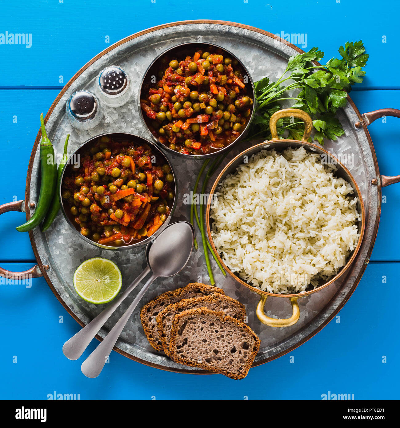 Vegan curry mit grünen Erbsen und Basmatireis auf einem blauen Tisch Tablett serviert, gesunde indische Speisen Stockfoto