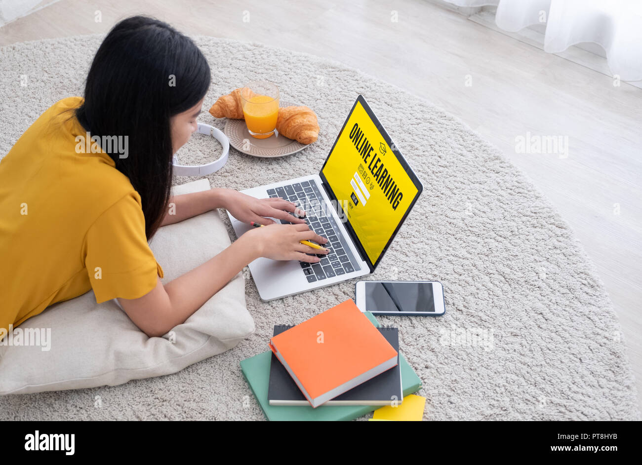Asiatische Studentin an e-learing Website auf Laptop Computer zu Hause anmelden. Frau liegend auf dem Teppich. Online lernen Lifestyle Stockfoto