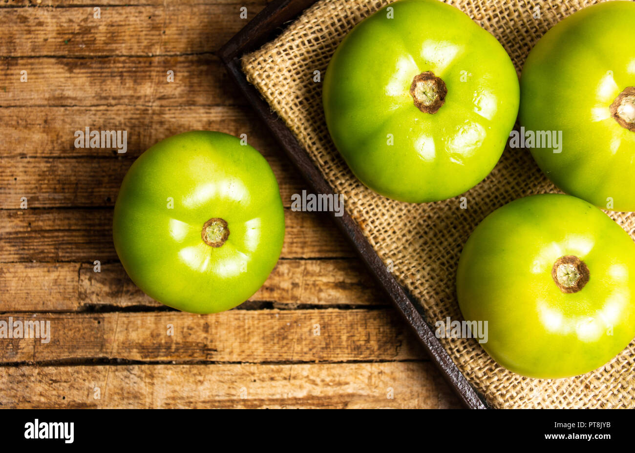 Grüne Tomaten auf einem rustikalen Holztisch Stockfoto