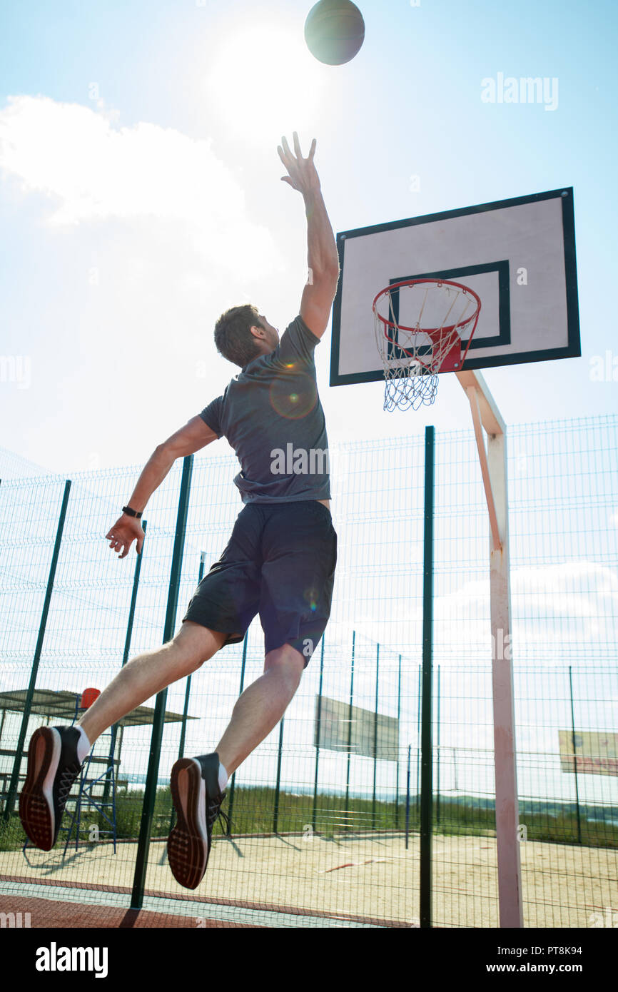 Volle Länge zurück Blick Porträt der jungen Sportler shooting Slam Dunk im Basketball Court, Kopieren im freien Raum Stockfoto
