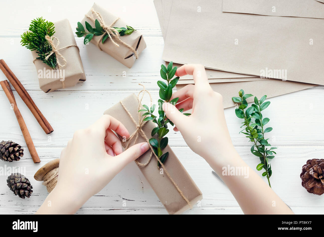 Prozess der Verpackung moderne Weihnachtsgeschenke mit natürlichen  Dekorationen auf weißem Hintergrund. Geschenke Boxen in Handwerk Papier mit  Garn und grüne Zweige Stockfotografie - Alamy