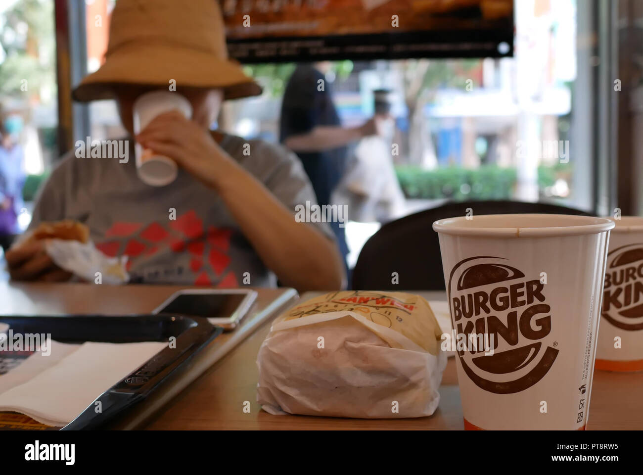 Taipei, Taiwan - August 17, 2018: Motion Blur von Frau Burger essen und trinken heißen Kaffee bei Burger King fast food Restaurant Stockfoto