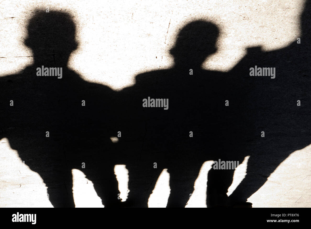 Verschwommene Silhouetten und Schatten der drei Mann auf Stadt Bürgersteig in der Nacht Stockfoto