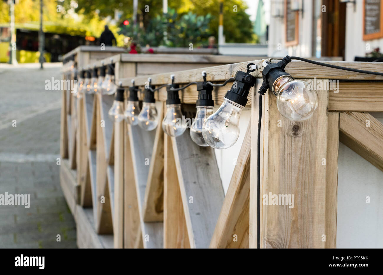 Eine Linie von kabelgebundenen Glühbirne edison Lampen mit LED-Glühlampen auf einer hölzernen Geländer außerhalb einer Coffee Shop in Norwegen. Stockfoto
