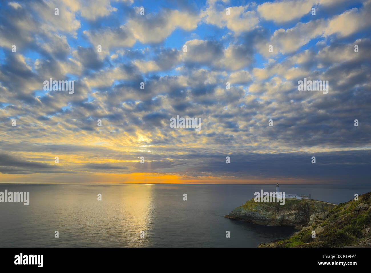 Abend Landschaft der untergehenden Sonne und dramatischer Abendhimmel mit Blick aufs Meer in Richtung South Stack Lighthouse, Anglesey, Nordwales. Altocumului. Stockfoto