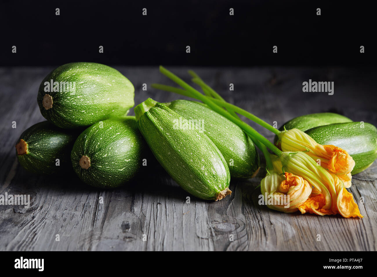 Zucchini und Zucchini Blüten. Frische grüne Zucchini mit Blumen auf rustikalen Hintergrund. Stockfoto