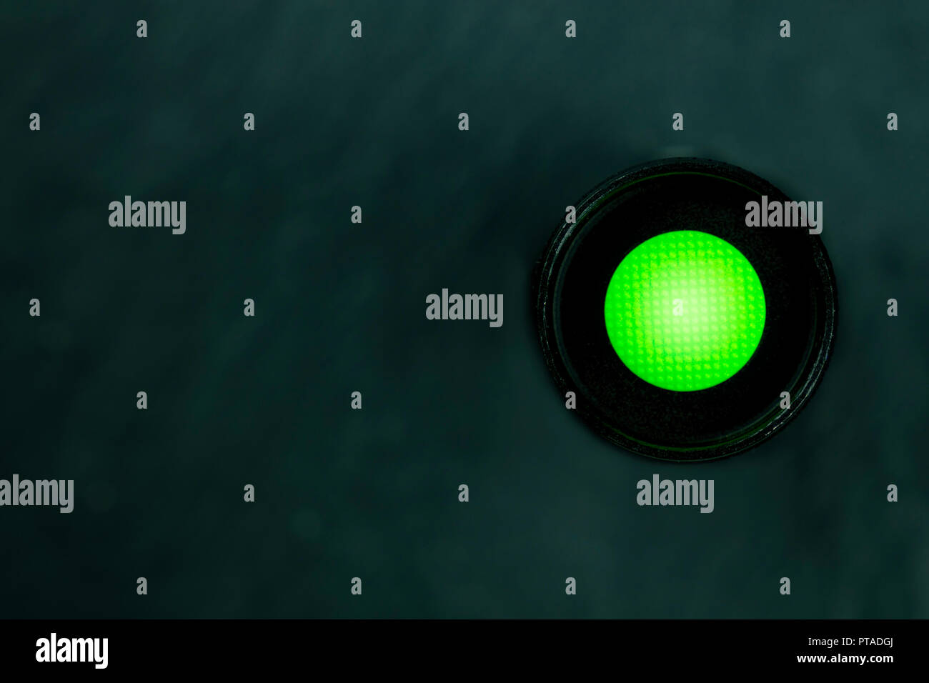 Ein Foto von einer lebhaften grüne Taste auf einem dunklen Panel mit einem Platz für Text Stockfoto