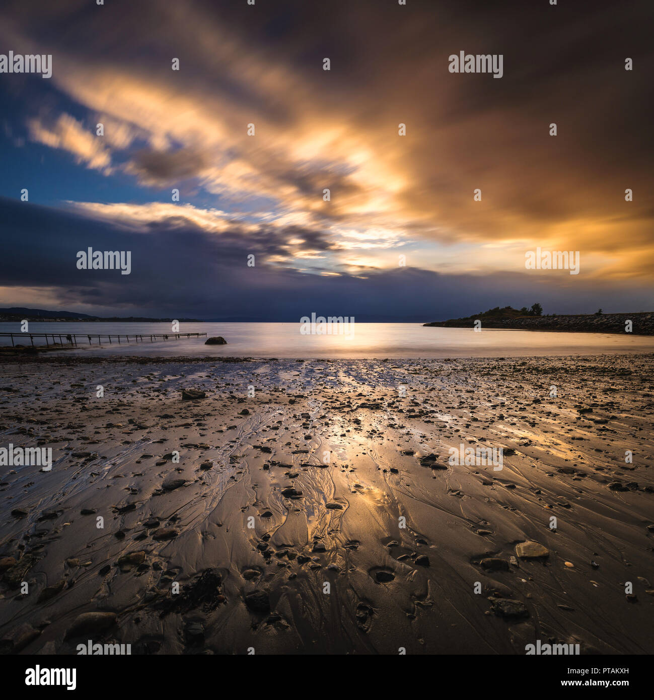 Sonnenuntergang von den Trondheimsfjorden, Strand in Vaeresholmen, Vaere. Lange Belichtung auf fließende Wolken und welligen Wasser. Stockfoto