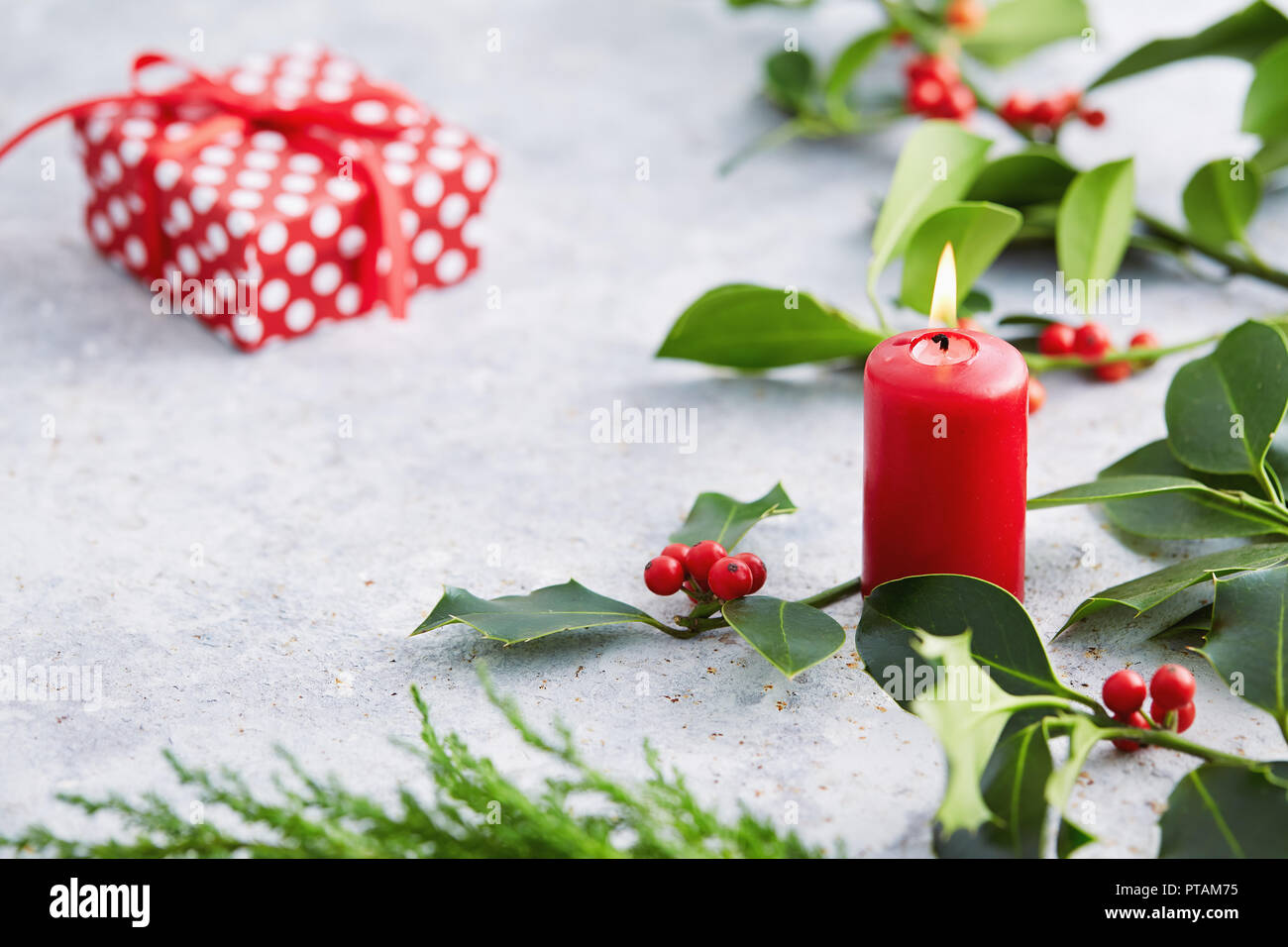 Weihnachtsschmuck, Kerzen mit immergrünen Dekorationen. Holly Blätter mit roten Beeren. Stockfoto
