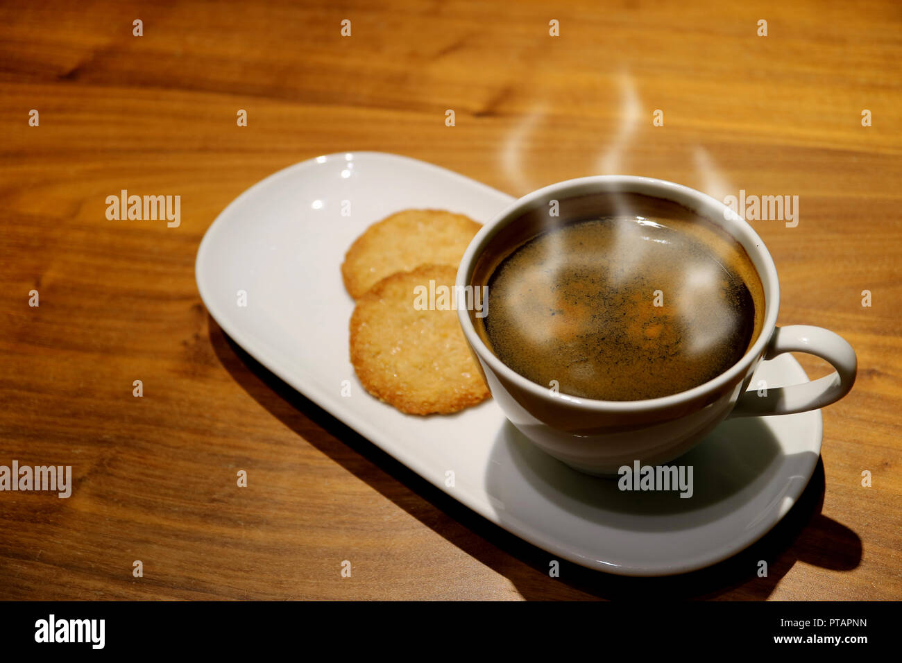 Tasse heißen Kaffee mit Rauch serviert mit Butter Cookies auf dem hölzernen Tisch Stockfoto