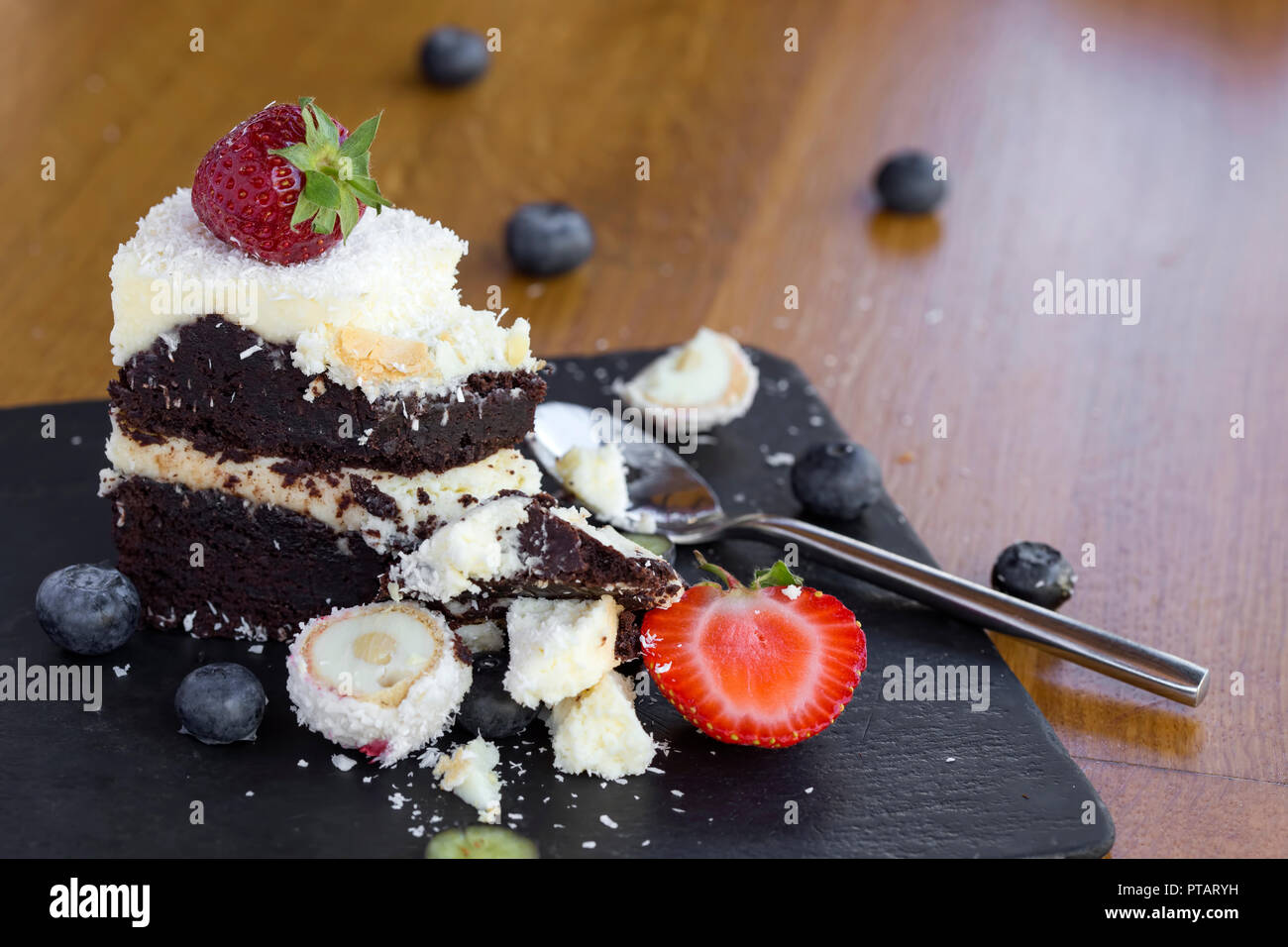 Schokolade Kuchen mit weißer und dunkler Schokolade, Früchte und Kokosnuss auf Schiefer Stockfoto