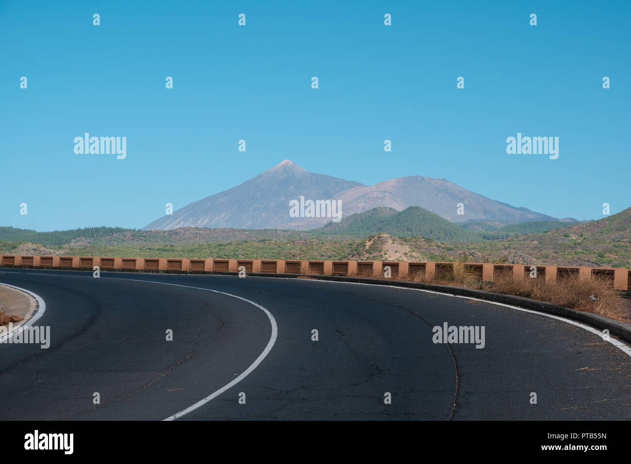 Asphaltierte Straße/Straße, Kurve in schöner Landschaft, Berg (Pico del Teide) und blauer Himmel, Teneriffa Stockfoto