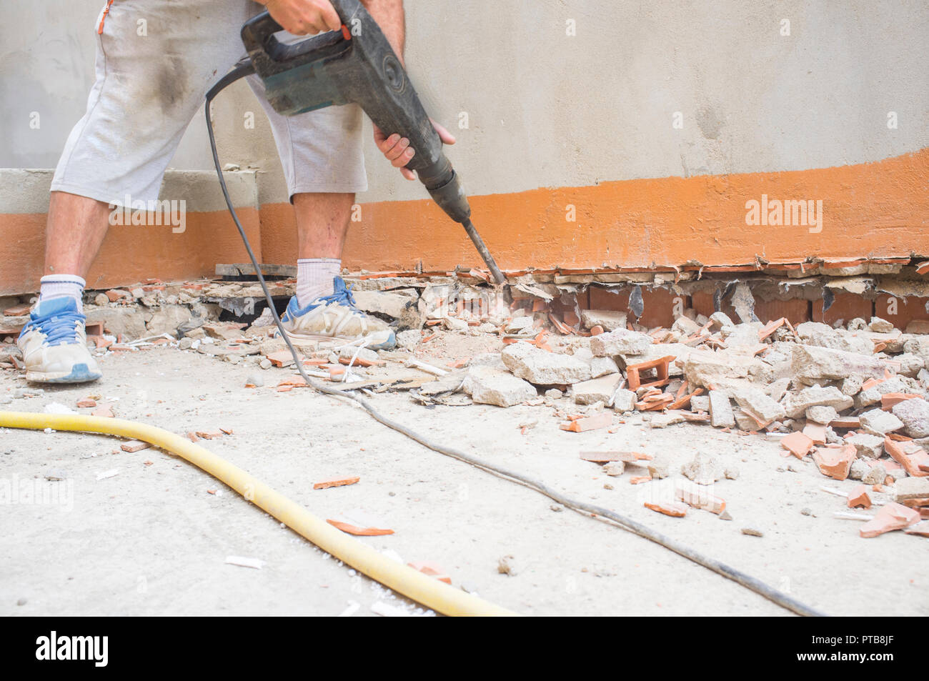 Bauarbeiter Grat entfernen aus der Sockelleiste Wand mit presslufthammer  Werkzeug. Etage voller Schutt Stockfotografie - Alamy