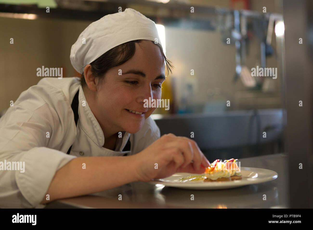 Köchin garnieren Essen auf dem Teller Stockfoto