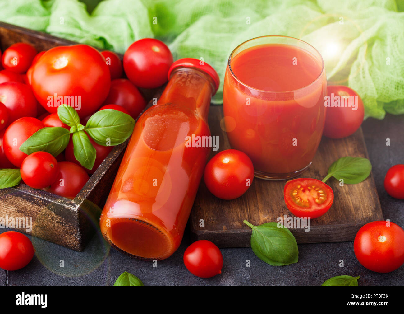 Flasche frische organische Tomatensaft mit frischen, rohen Tomaten in Kiste auf Küche Hintergrund. Stockfoto