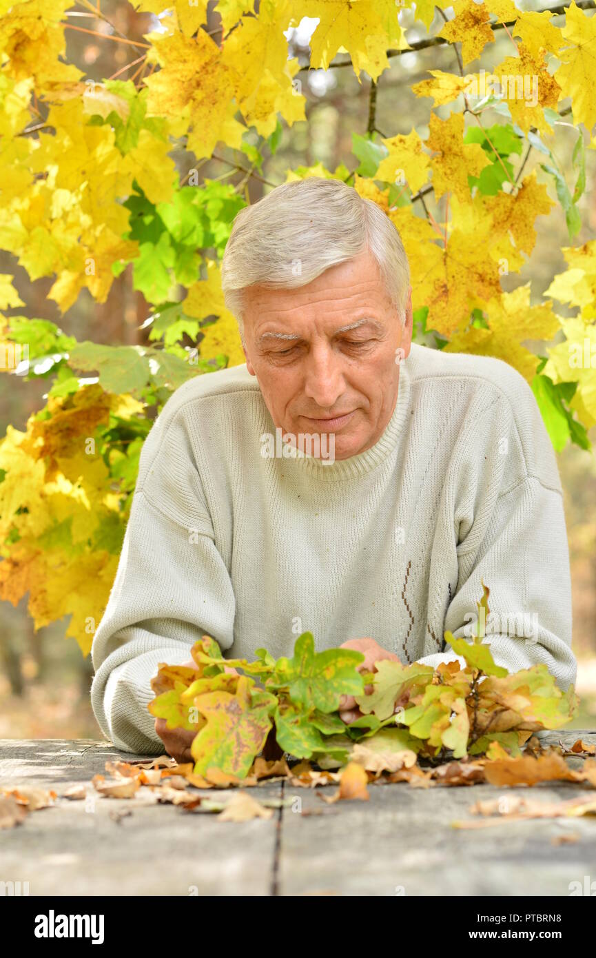 Portrait von Reifen nachdenkliche Menschen am Tisch im Freien über Herbst Hintergrund sitzen Stockfoto