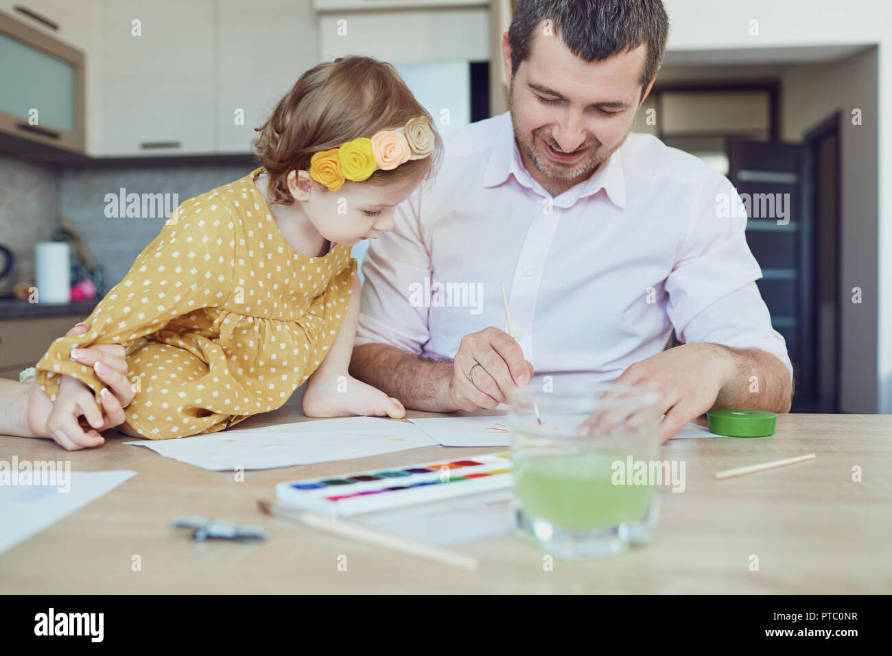Mutter, Vater und Kind zeichnen zusammen am Tisch. Stockfoto