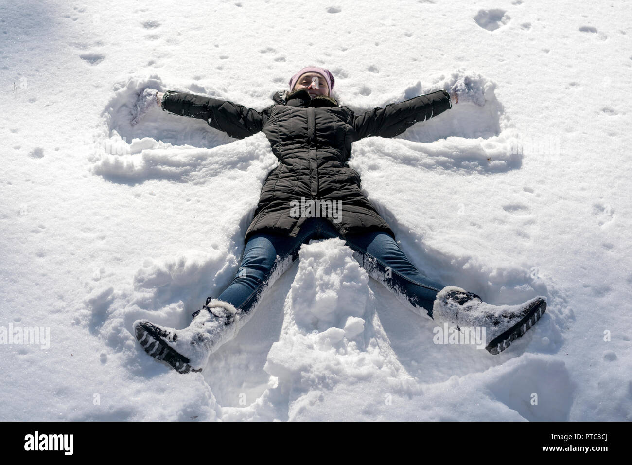 Glückliche junge Frau liegend auf Snow Fell im Winter. Junge Frau Scherz auf Schnee im Winter. Stockfoto