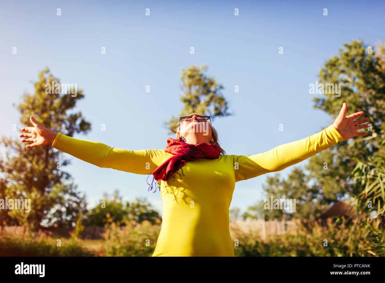 Frau mittleren Alters freies und glückliches Gefühl am Ufer auf Herbst Tag. Ältere Dame heben die Hände hoch Stockfoto