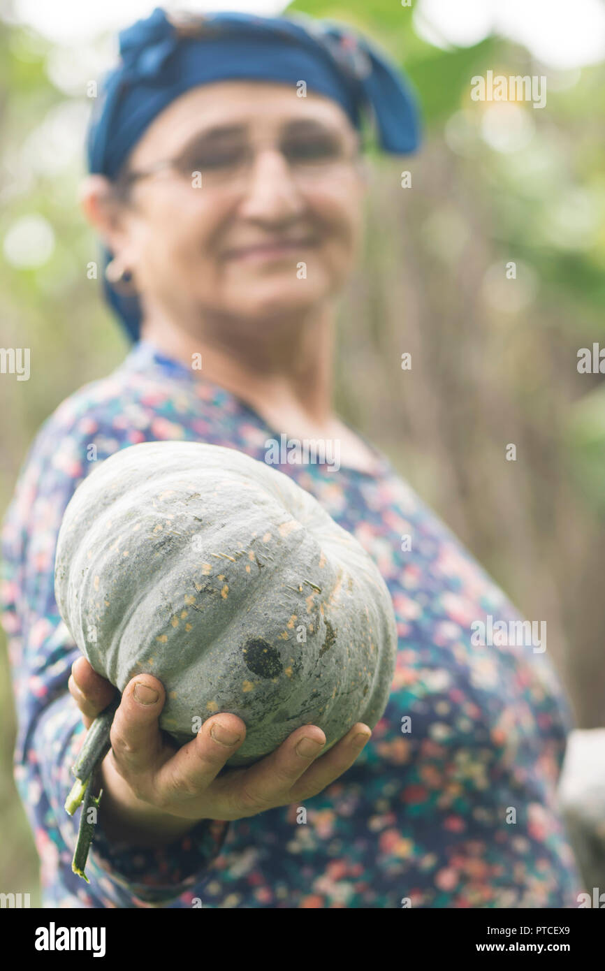 Gerne ältere muslimische Frau Bauer Holding einen einzigen Kürbis in der rechten Hand am Garten Stockfoto