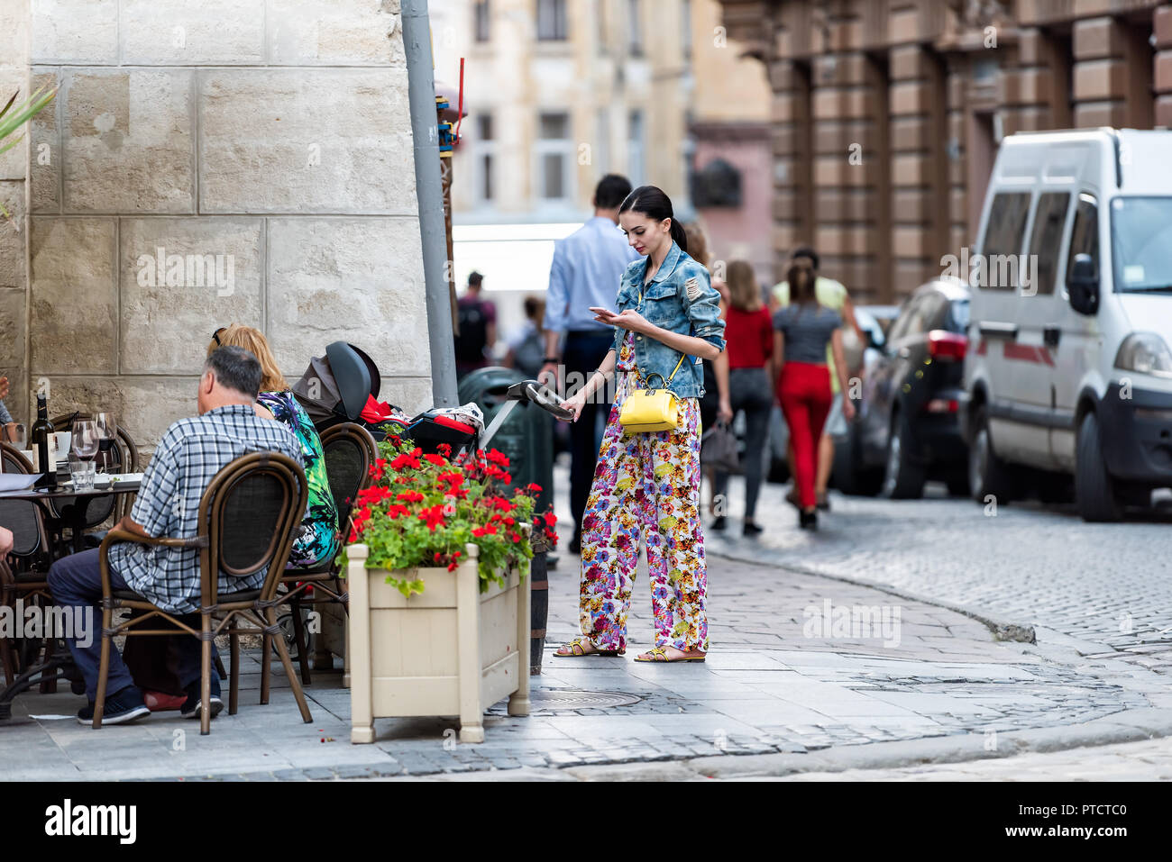 Lemberg, Ukraine - 30. Juli 2018: Die slawischen Osteuropa ukrainische Frau, die in der historischen Ukrainischen polnische Stadt in der Altstadt Straße mit Kopfsteinpflaster, baby Stockfoto