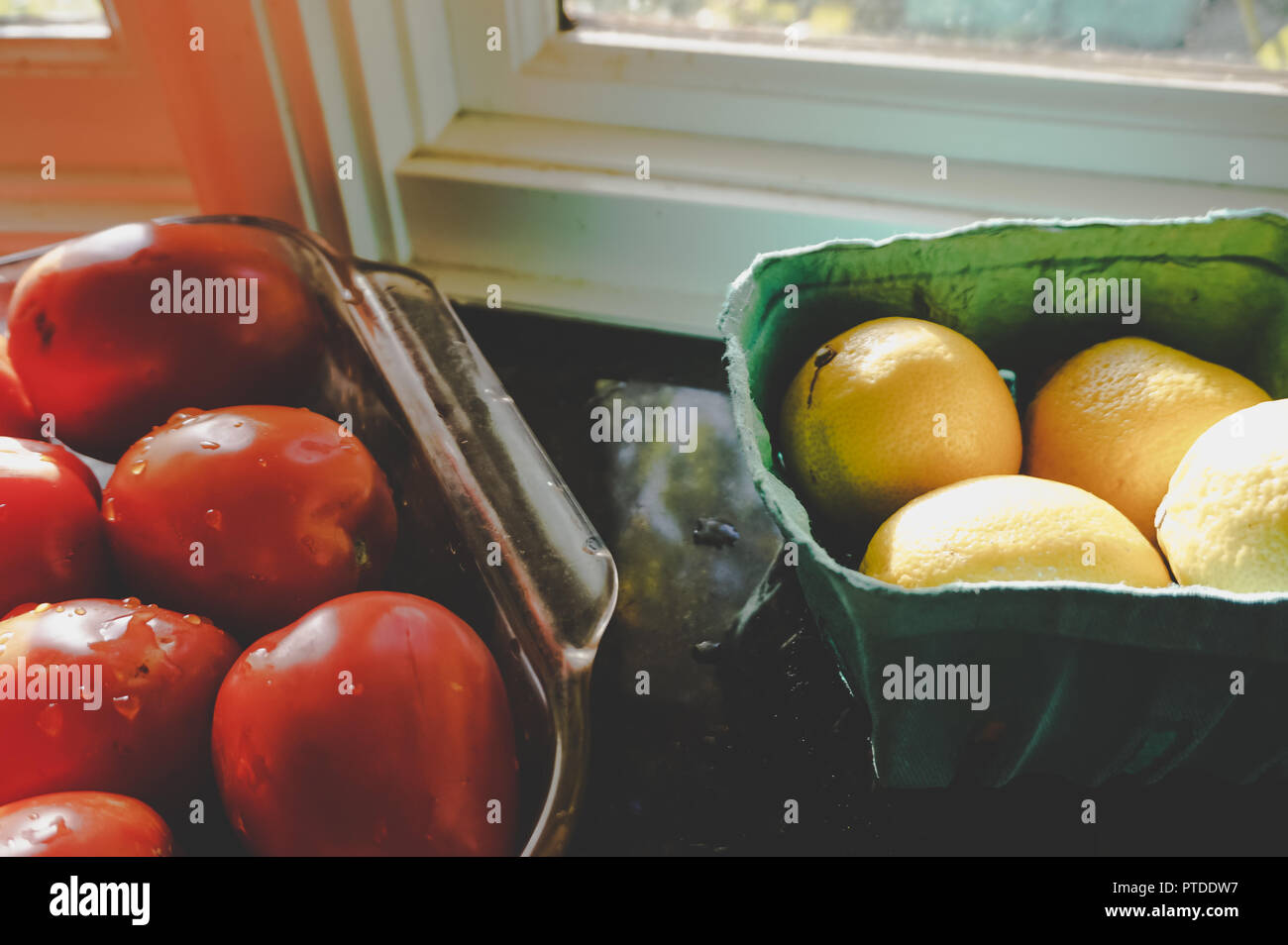 Bio Zitronen und roma Tomaten aus der Bauernmarkt Aalen in natürlichem Sonnenlicht auf Marmor Fensterbank in der Küche gourmet Küche Stockfoto
