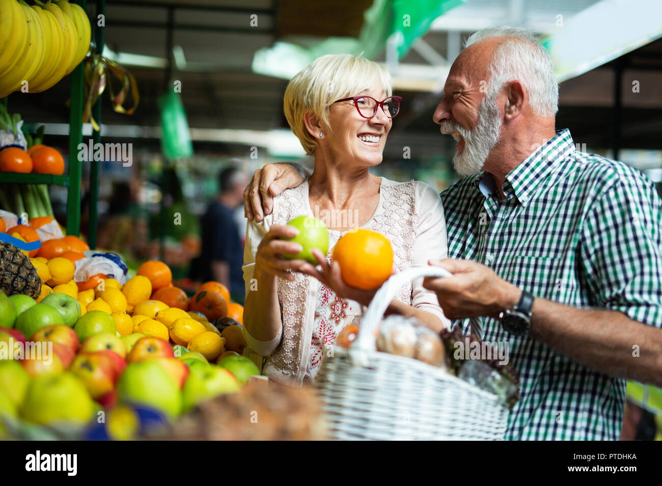 Lächelnd senior Paar hält Korb mit Gemüse auf dem Markt Stockfoto