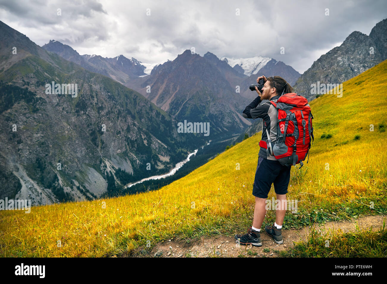 Mann Fotograf mit grossen Rucksack und Kamera, Foto in die Berge. Reisen Lifestyle Konzept Abenteuer aktiv Urlaub im Freien Stockfoto
