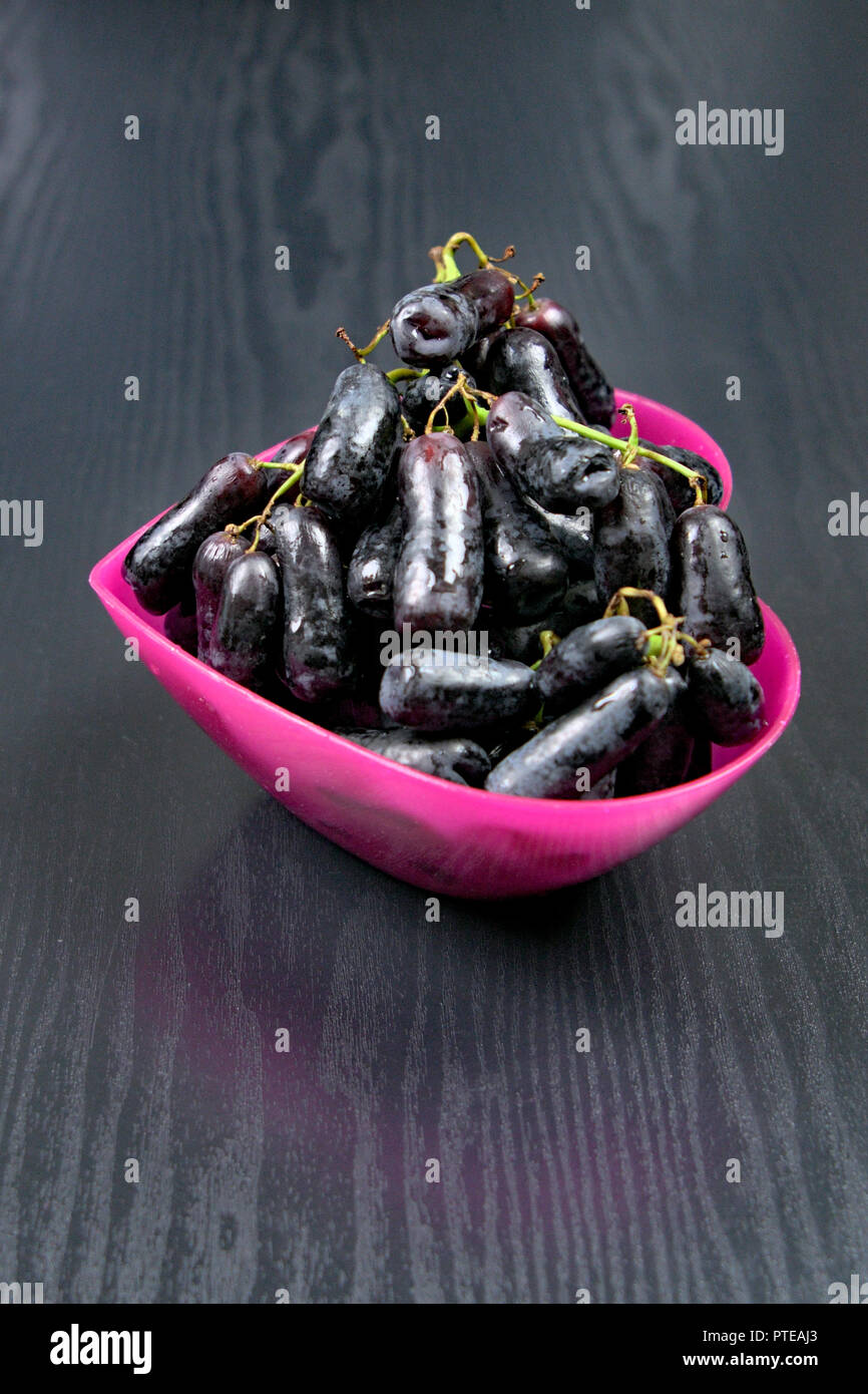 Lange schwarze Trauben in einem rosa Herzförmige Schale Stockfoto