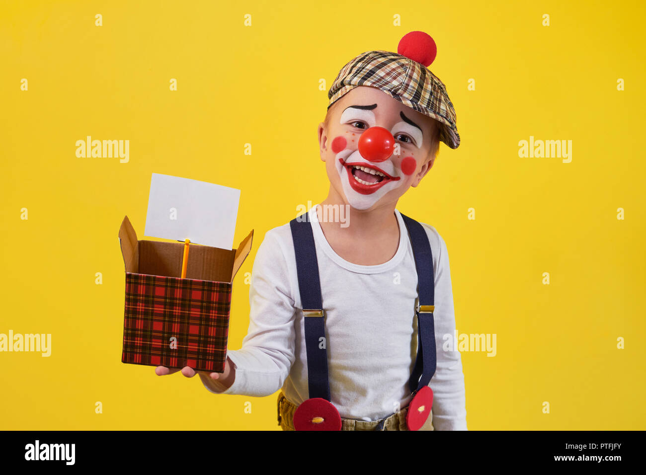 Funny kid Clown auf gelbem Hintergrund. Schönen verspielten portrait Kind Junge Narren in Make-up. Ausdruck Gesicht Freude, Lächeln, Spaß, fröhlich. 1 April Fool's Day Konzept. Stockfoto