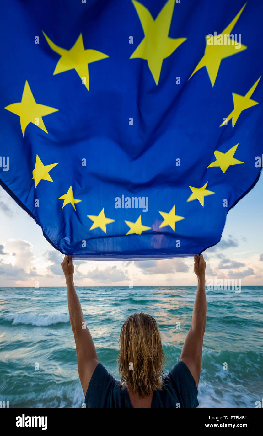 Mann hält EU Europäische Union Flagge vor der Mediterranen Wellen Stockfoto
