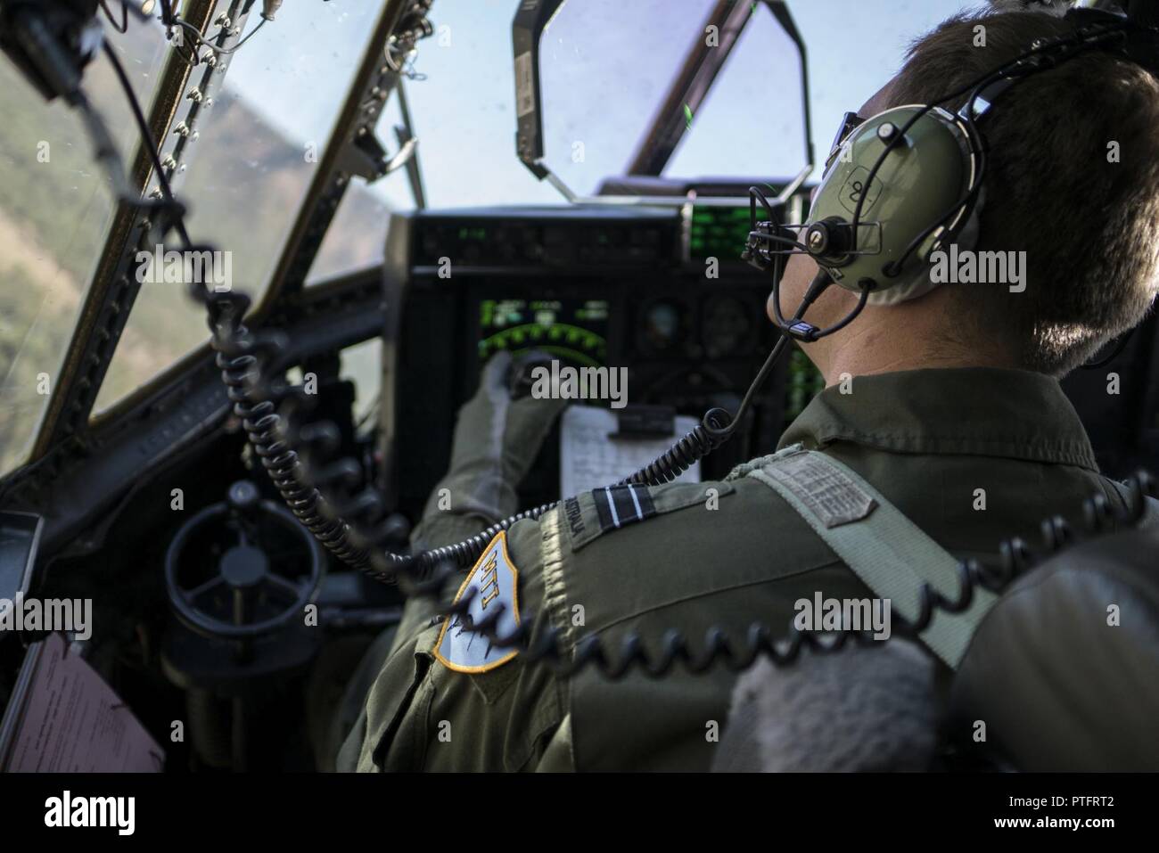 Ein Nr. 37 Squadron der Royal Australian Air Force Pilot schaut aus dem Fenster eines RAAF C-130J Hercules während einer ungleichen Formationsflug mit der US Air Force 17 Special Operations Squadron MC-130J Commando II Juli 12, 2017 in Queensland, Australien. Talisman Sabre 2017 bot die Möglichkeit, an der Weiterentwicklung der Interoperabilität mit Kollegen aus der RAAF durch tägliche Airborne operations low-level Bildung arbeiten, leiten die Luftbetankung Punkt zu gehören, sowie Personal- und Cargo Fallschirmabwürfen. Stockfoto