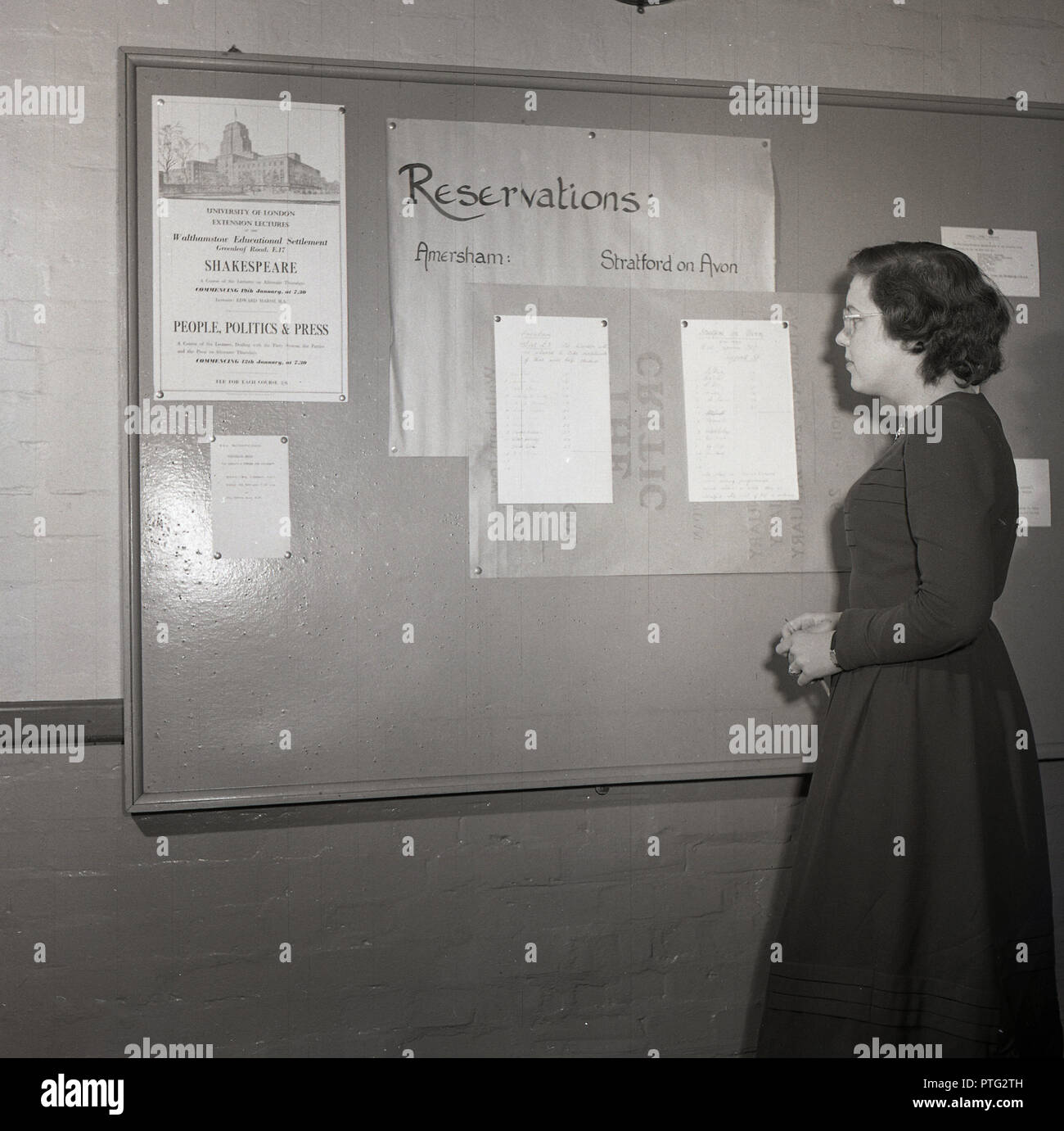1950er Jahre, junge Dame Student an eine Liste von Namen für Ausflüge nach Amersham und Stratford-upon-Avon auf einem Schild an der Universität von London suchen, mit einer Benachrichtigung über einen Kurs von Shakespeare Erweiterung Vorträge. Stockfoto