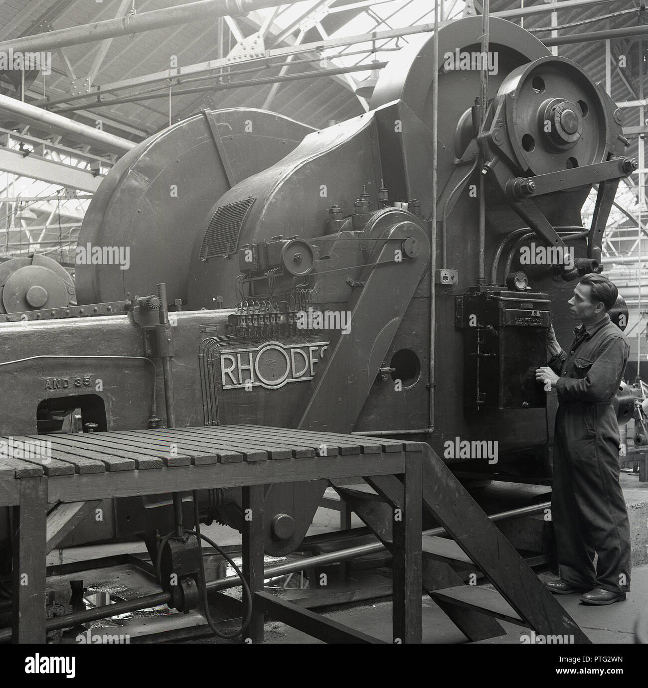 1950er Jahre, historischen, immer bereit, Batterie Fabrik, männlichen Arbeitnehmer stand neben einem großen Rhodos Blech, eine strangpresse Für die Batterie Gussteile, England, UK. Stockfoto