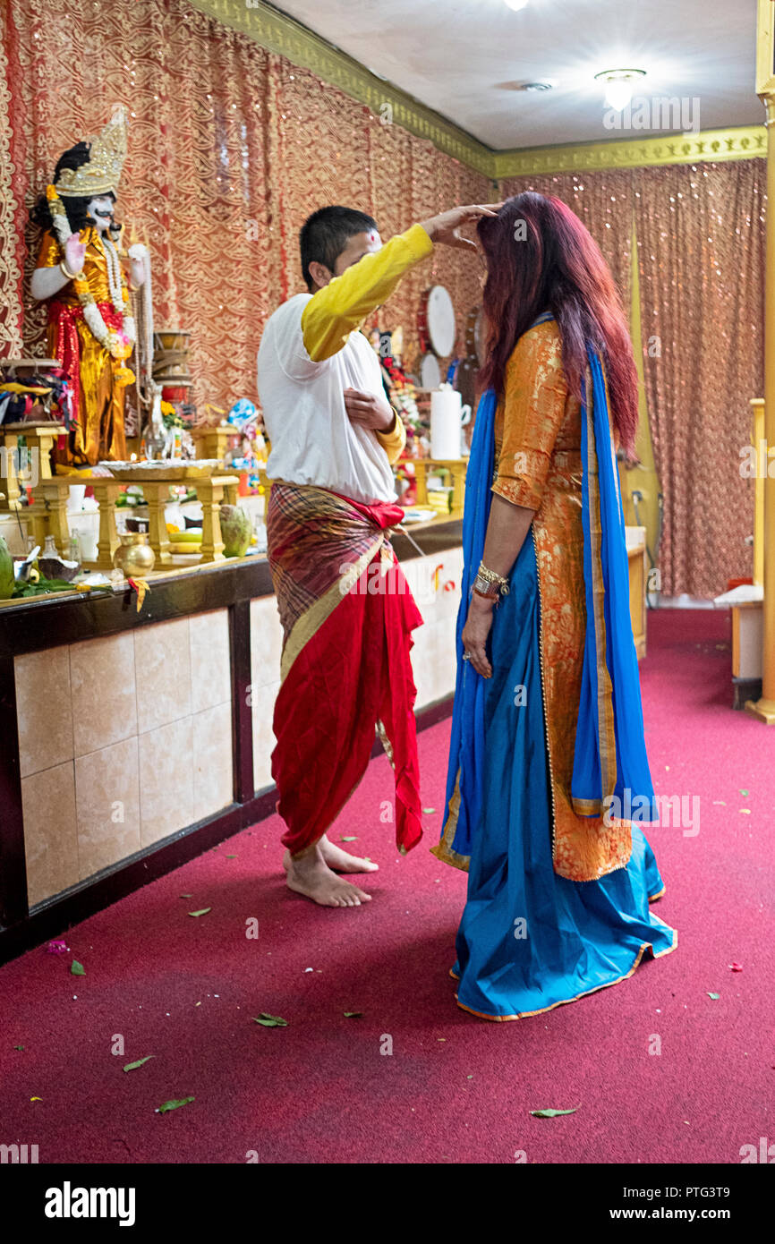 Eine Frau in einem schönen Sari erhält einen persönlichen Segen an einem hinduistischen Mandir (Tempel) in Richmond Hill, Queens, New York. Stockfoto