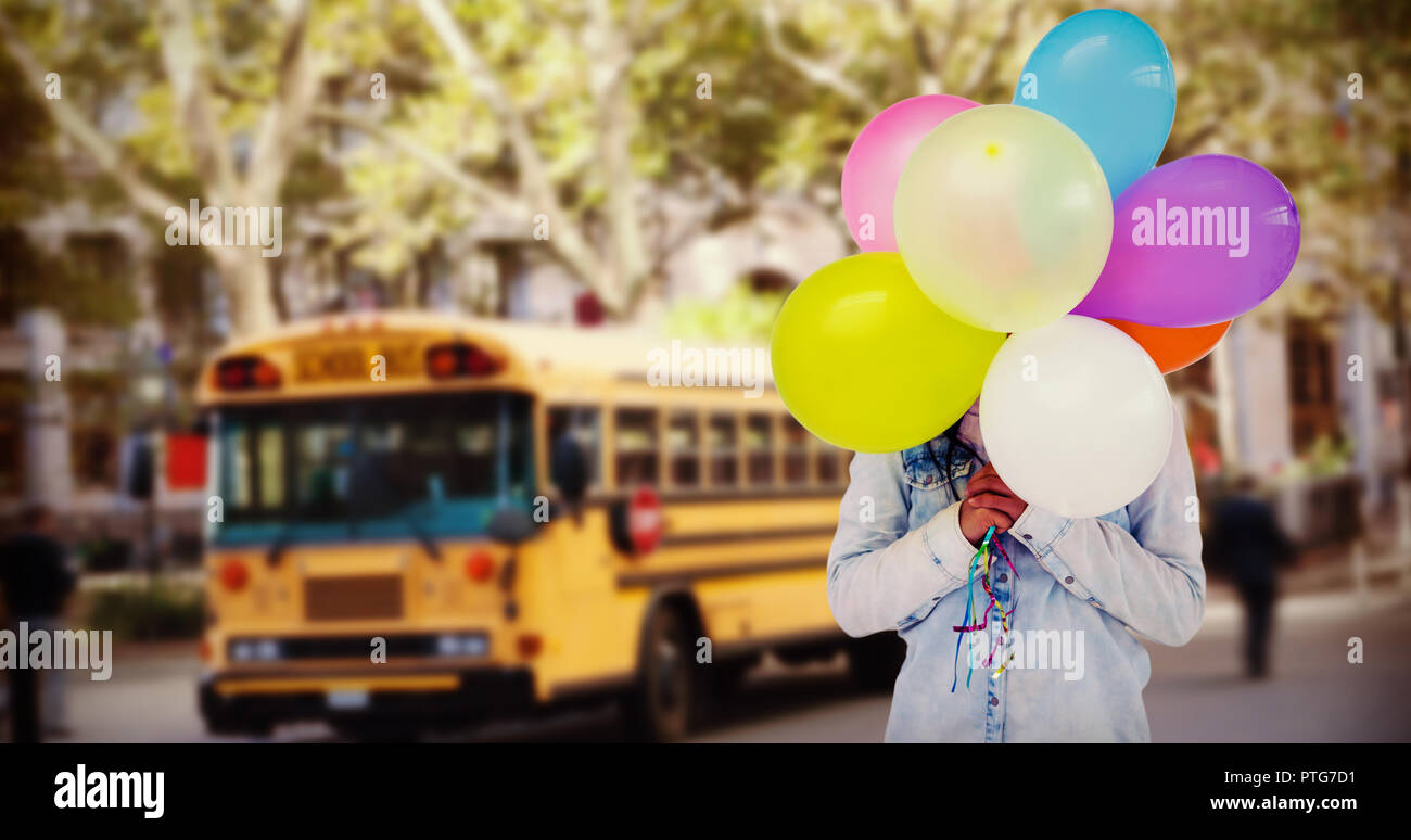 Das zusammengesetzte Bild der Frau ihr Gesicht verstecken mit Bündel von bunten Luftballons Stockfoto