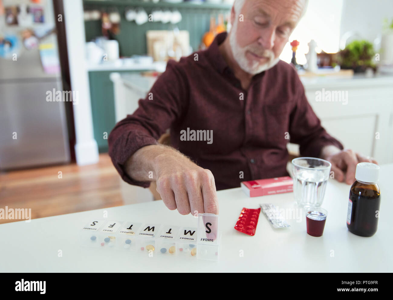 Ältere Menschen organisieren Pille Box am Küchentisch Stockfoto